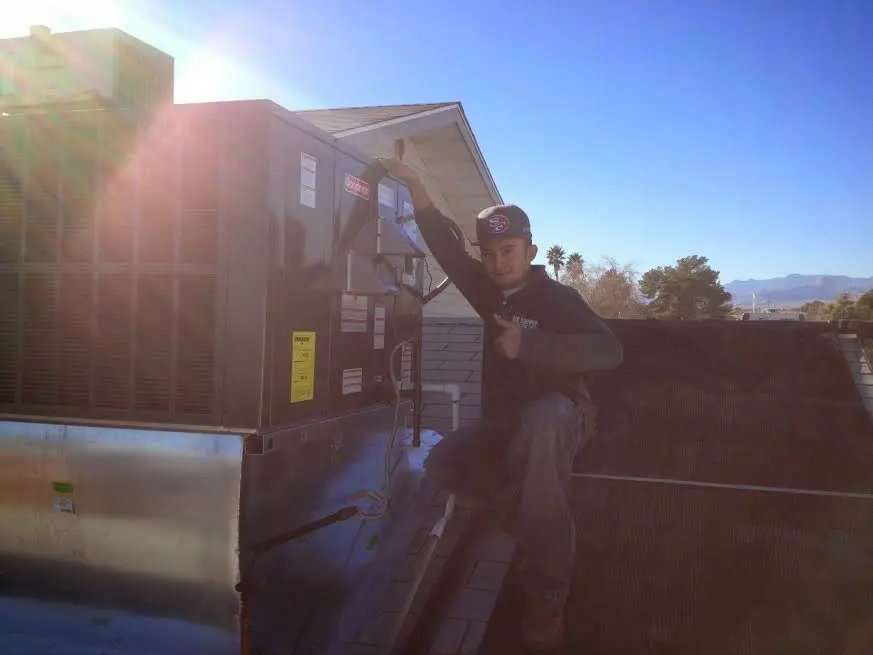 HVAC technician performing Heat Pump Repair on a rooftop unit in Warner Robins