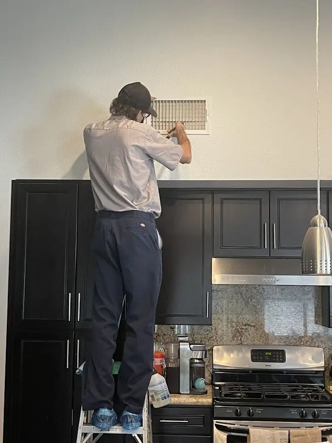 Technician inspecting an air vent during HVAC service in Warner Robins